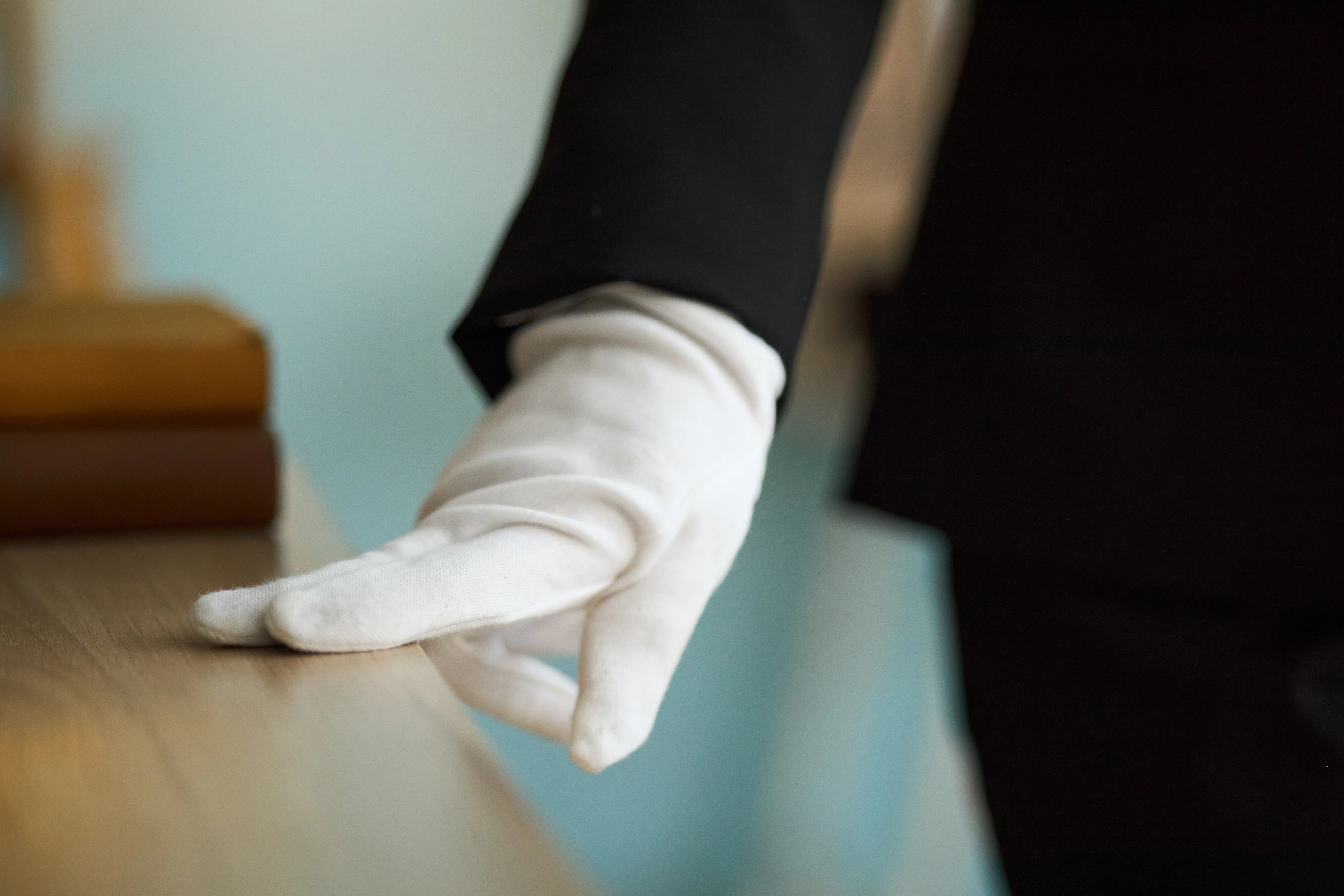 White glove service — attendant wearing white gloves resting hand on polished surface, representing precision and care by Cadiz & Lluis